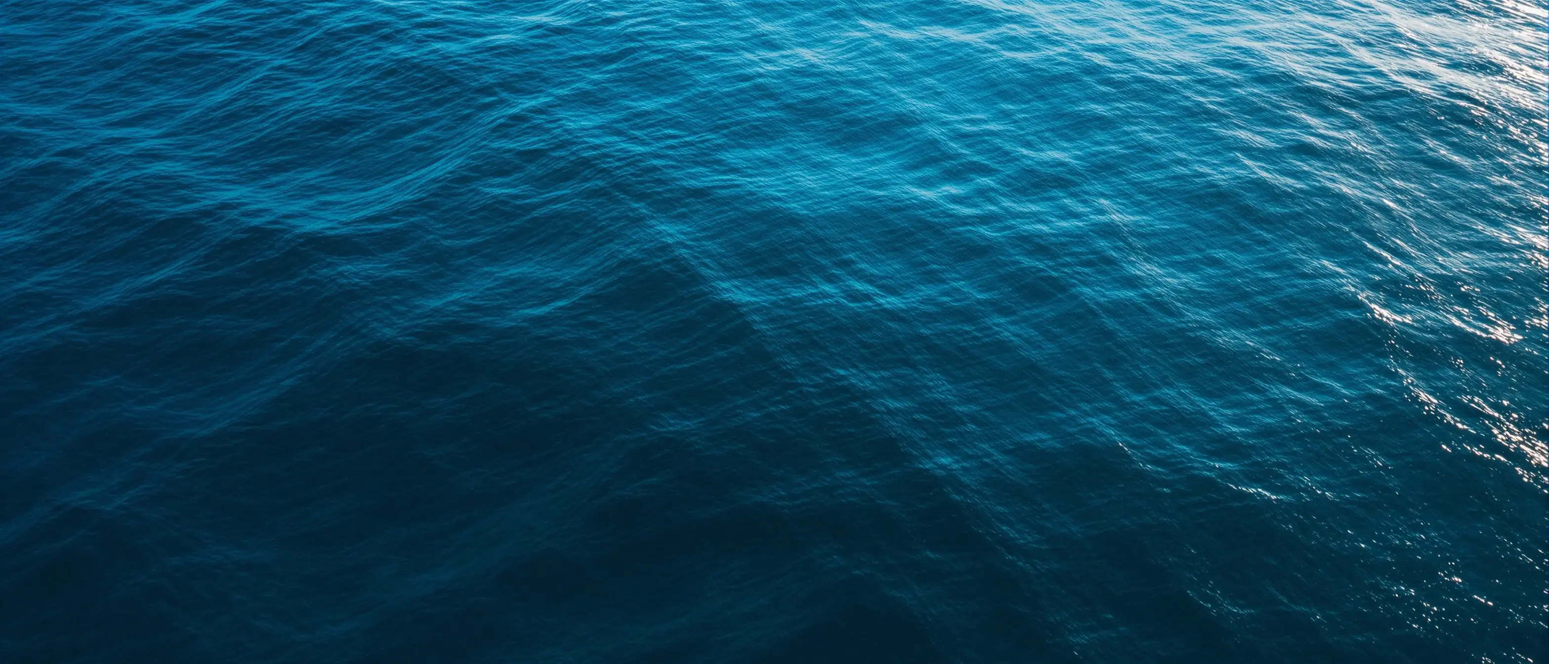Serene aerial view of calm turquoise ocean water at dusk representing the clarity and transparency of Open Water Rx pricing